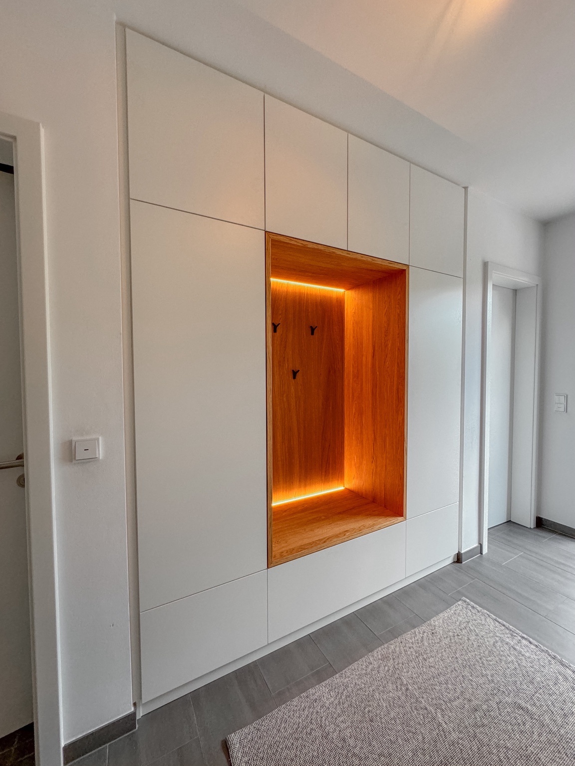 Weiße Garderobe mit beleuchteter Holznische